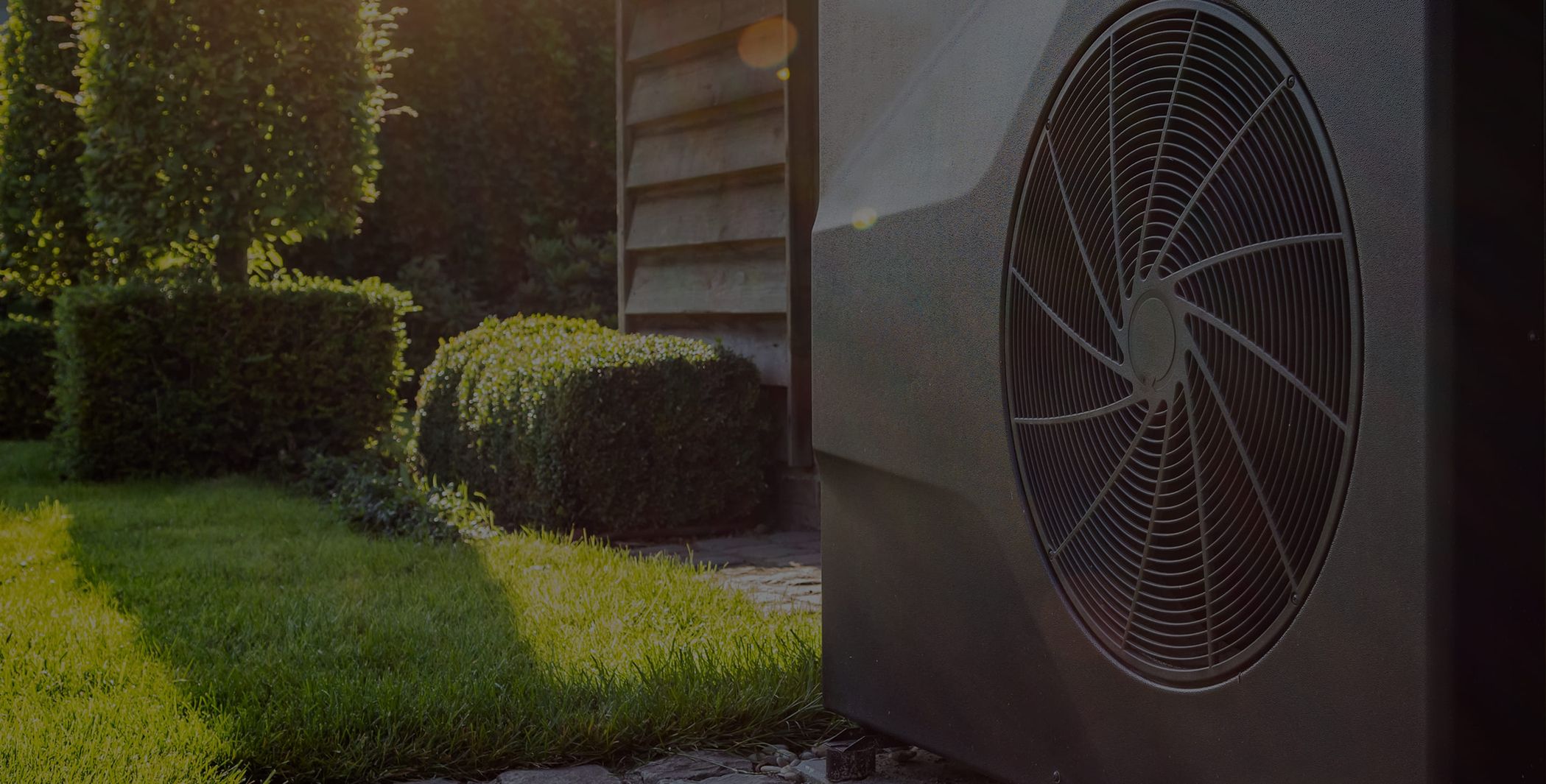 Außeneinheit einer Wärmepumpe im Garten mit Pflanzen